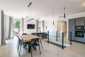 A modern interior with a dining area, sofa, kitchen, and a staircase leading to an upper level. - Sant' Anna Deluxe (Menaggio)