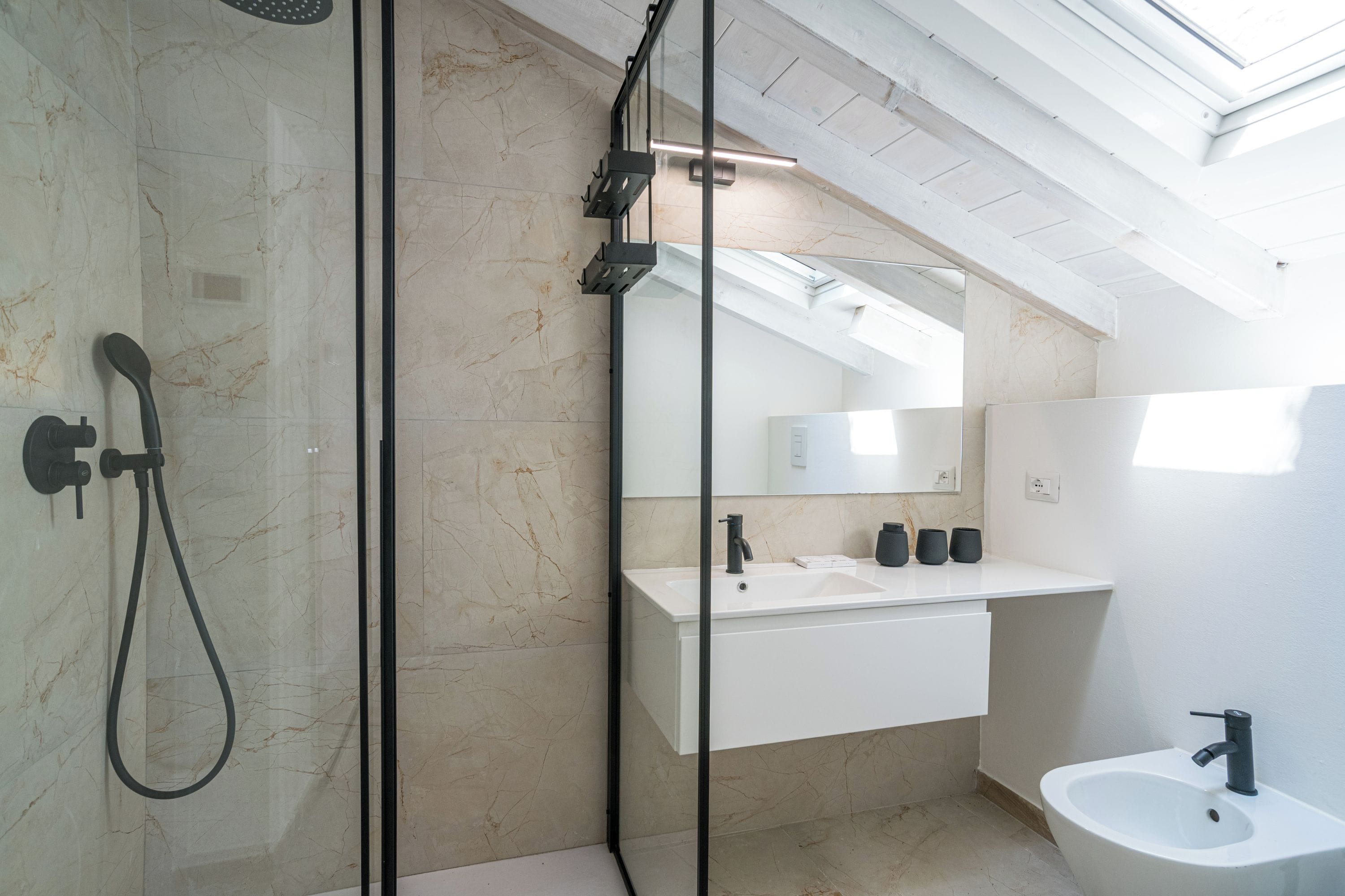 Une salle de bain moderne avec une douche à parois de verre, un lavabo blanc et un bidet.
