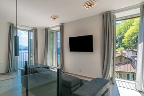 Ein modernes Wohnzimmer mit großem Fenster, einem Flachbildfernseher und einer Glastrennwand.