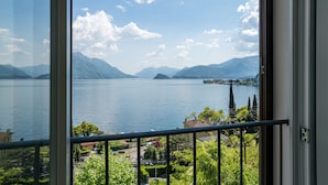 A view of a lake with mountains in the background, a balcony with a railing, and some greenery. - Sant' Anna Deluxe (Menaggio)