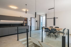 A modern kitchen with a dining area, a staircase, and a view of the outdoors. - Sant' Anna Deluxe (Menaggio)