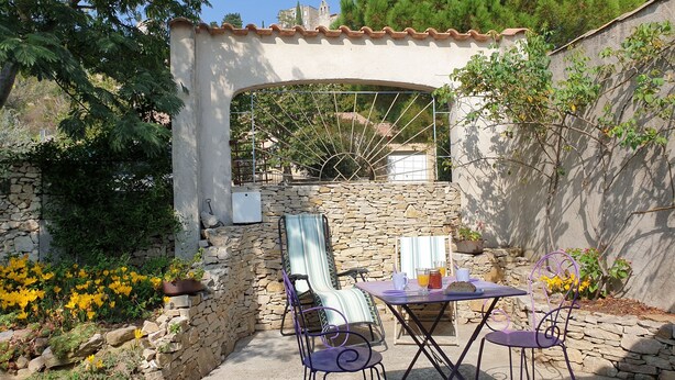 Eine Terrasse mit Steinmauern, einer Pergola und Sitzgelegenheiten im Freien.
