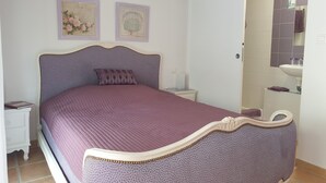 Ein Schlafzimmer mit Bett, Nachttisch und einem durchgegangenen Tür sichtbaren Badezimmer.