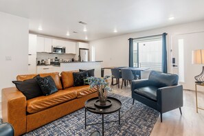 Ein modernes Wohnzimmer mit einer Couch, einem Couchtisch und einem Essbereich mit Tisch und Stühlen.