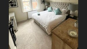 A bedroom with a large bed, a dresser, a window with a blind, and a radiator. - Spacious House in Guildford  (Guildford)
