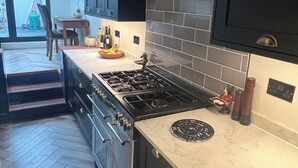 A modern kitchen with dark cabinetry, a gas stove, and a marble countertop. - Spacious House in Guildford  (Guildford)