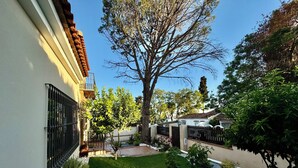 Un quartier résidentiel avec une pelouse bien entretenue, un grand arbre et une maison dotée d’un toit en tuiles et d’un mur en briques.