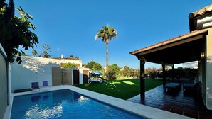 Une piscine à l’eau d’un bleu limpide, entourée d’un patio aménagé avec des meubles d’extérieur.