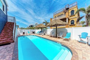 A swimming pool with lounge chairs and umbrellas, a staircase, and a building with balconies. - Seagrass Sunsets Unit 4 (Bradenton Beach)