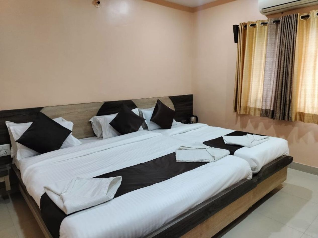 A double bed with white and black bedding, a wooden headboard, and a nightstand with a lamp.