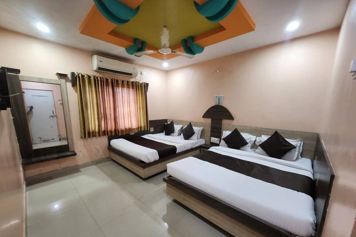 Une chambre d’hôtel avec deux lits, un ventilateur de plafond, un appareil de climatisation et une porte.