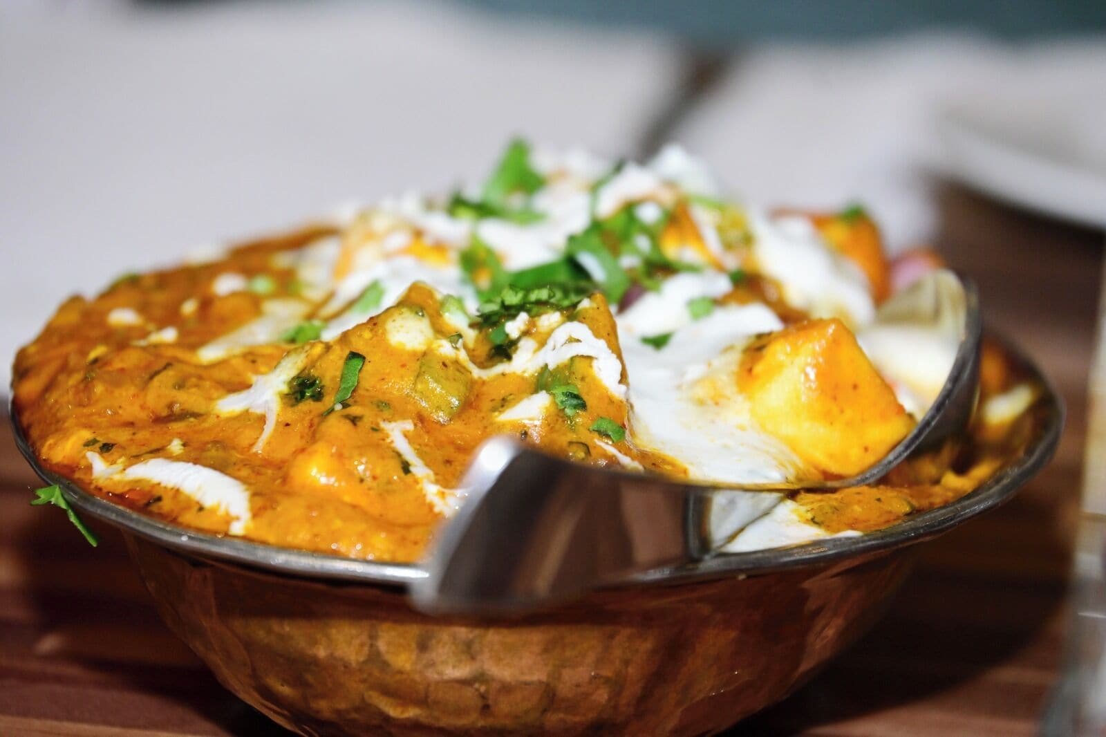 Eine Schüssel Curry mit Paneer und einem Löffel.
