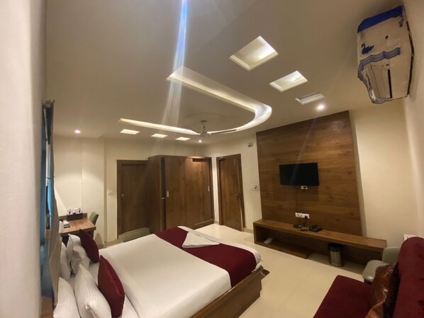 A modern hotel room with a bed, a desk, a TV, and a wooden wall panel. - HOTEL MANISHA INTERNATIONAL (Gaya)