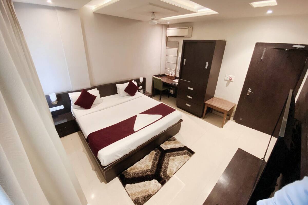 A modern bedroom with a large bed, a desk, and a wardrobe.