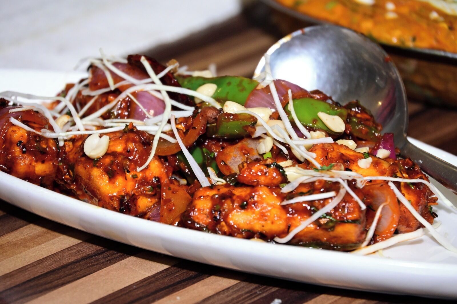 A dish with chicken, vegetables, and garnishes on a white plate.