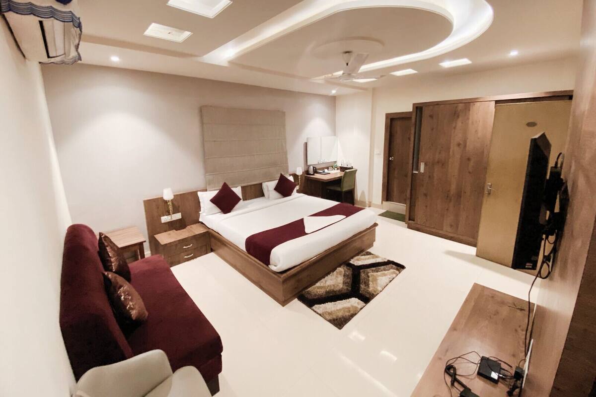 A modern bedroom with a large bed, bedside tables, a desk, and a wardrobe.