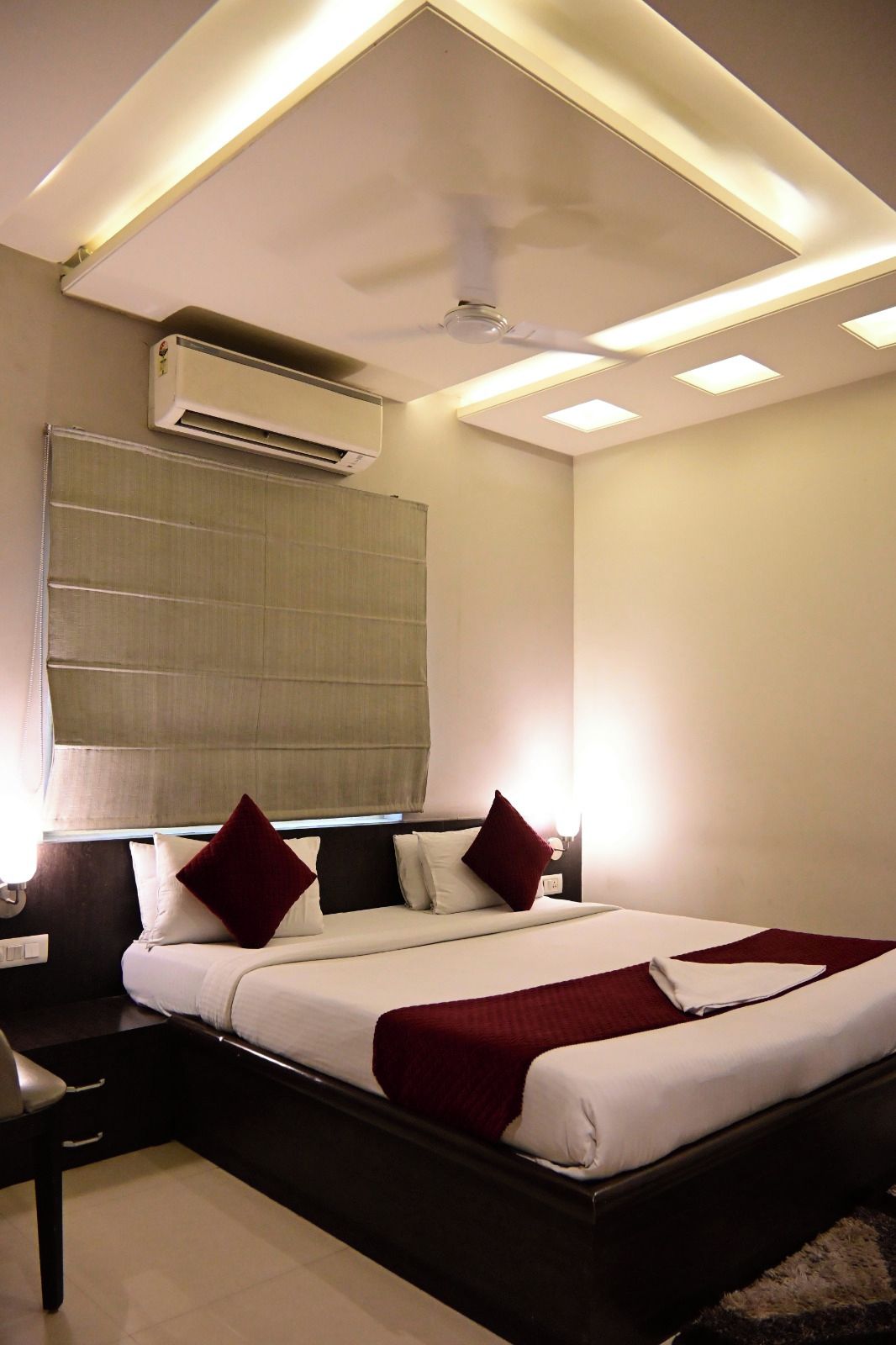A modern bedroom with a bed, bedside table, and an air conditioning unit.