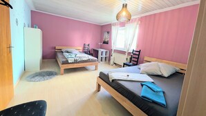 Een slaapkamer met twee bedden, een bureau, een stoel en een radiator.