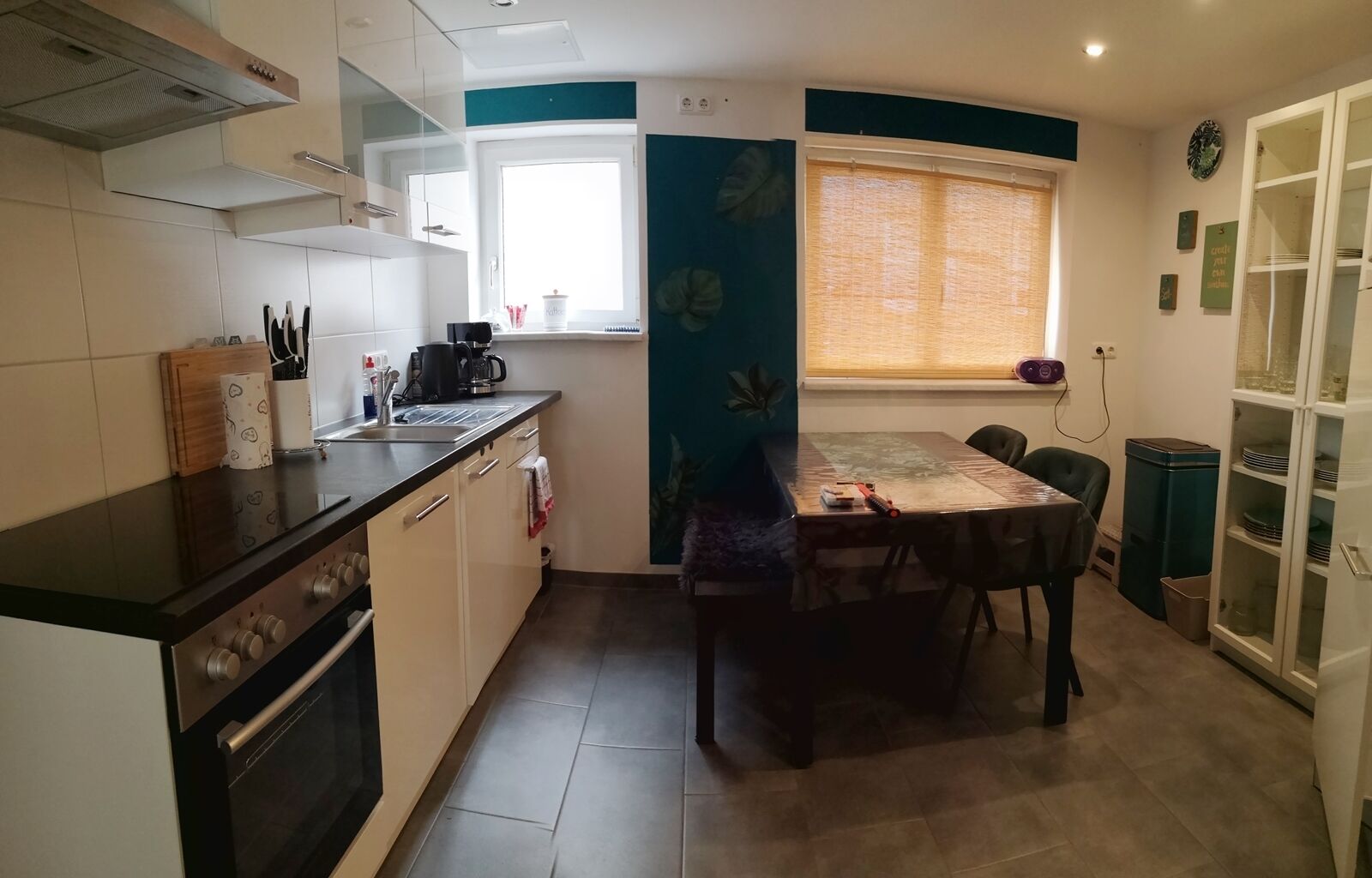 Een kleine keuken met een fornuis, spoelbak en eettafel.