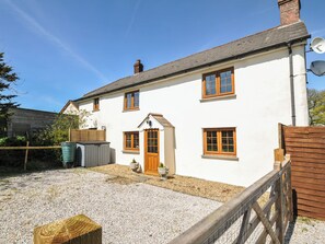 A two-story white house with a wooden door, multiple windows, and a gravel driveway. - Little Blagdon (Holsworthy)