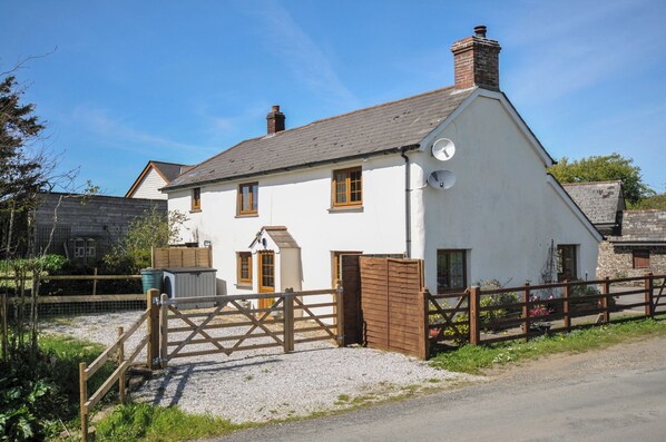 A white two-story house with a sloped roof, a wooden gate, and a gravel driveway. - Little Blagdon (Holsworthy)