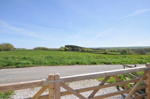 A rural landscape with a gravel path leading to a wooden gate. - Little Blagdon (Holsworthy)