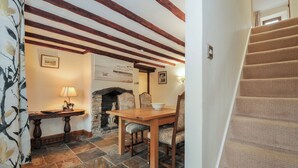 A dining area with a stone fireplace, wooden beams, and a staircase. - Little Blagdon (Holsworthy)