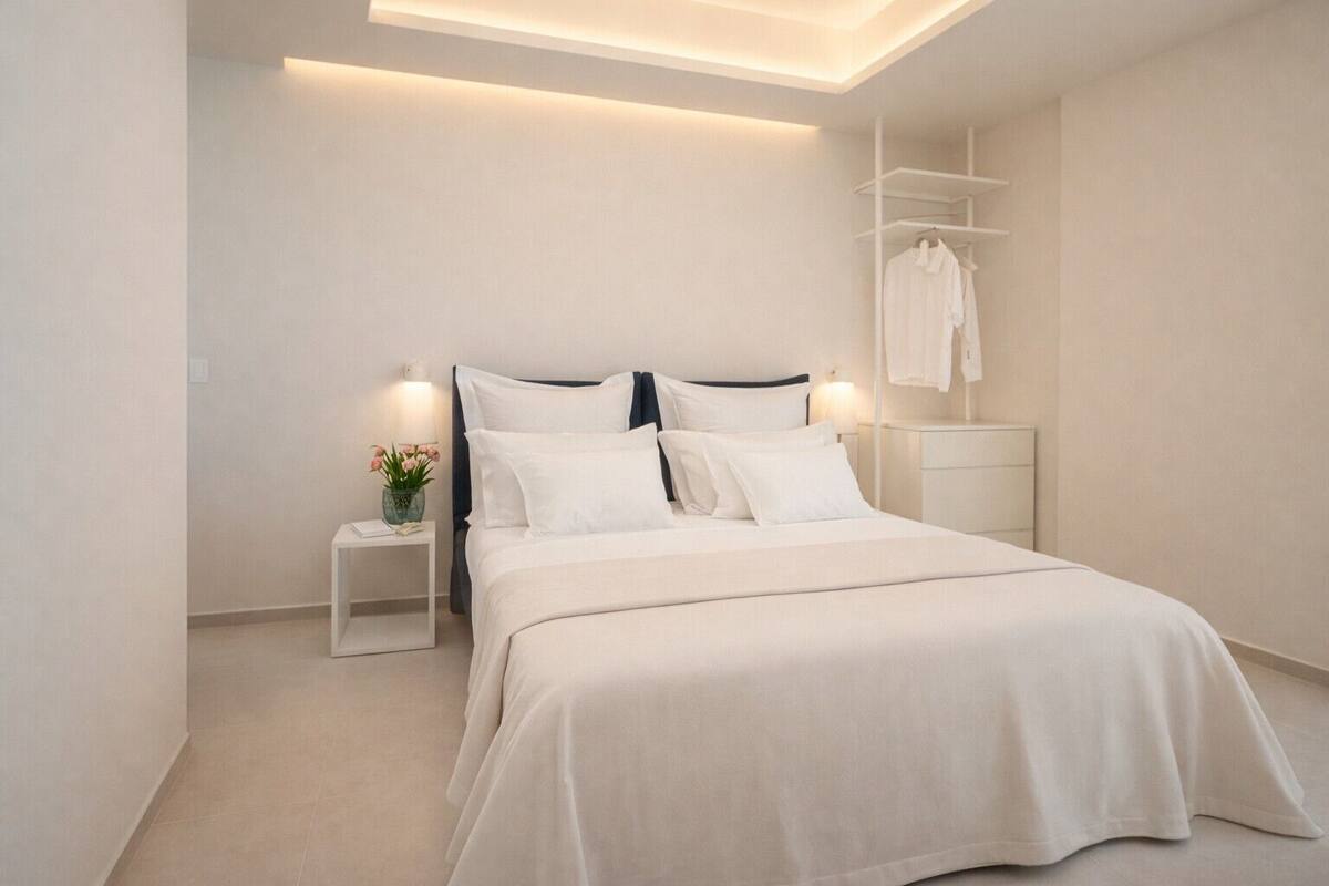 Une chambre moderne avec un grand lit, des tables de chevet, une petite table et une armoire intégrée.