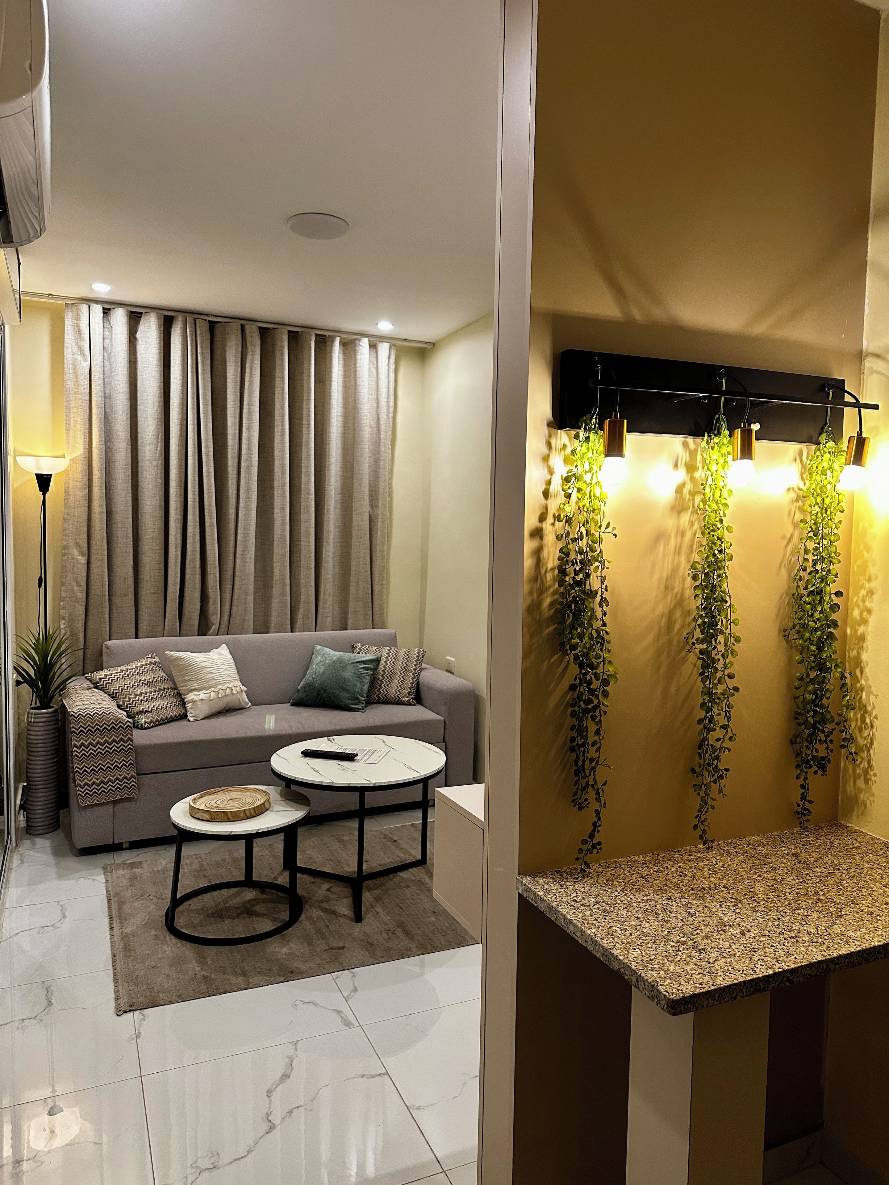 A modern living room with a sofa, coffee table, and a wall-mounted light fixture.