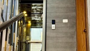 A modern entrance with a glass door, a wooden door, and a textured wall. - Beit Ahlan Suites (Amman)