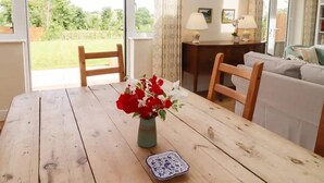 Een eetgedeelte met een houten tafel, een vaas rode bloemen en een blauw-wit bord.