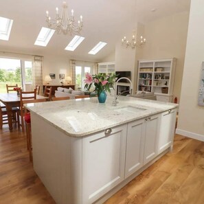 A spacious kitchen with a central island, white cabinetry, and a chandelier. - Beautiful Barn, Stunning Views, Parking & Garden (Gloucestershire)