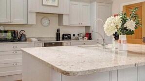 Een moderne keuken met een groot eiland, witte kasten en een dakraam.