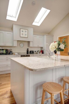 A modern kitchen with a large island, white cabinetry, and a skylight. - Beautiful Barn, Stunning Views, Parking & Garden (Gloucestershire)