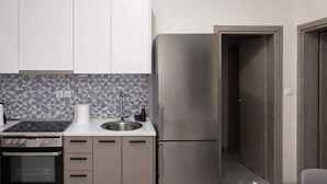 Een moderne keuken met een inbouwoven, een roestvrijstalen koelkast en een betegelde spatwand.