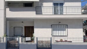 Een gebouw met twee verdiepingen, een balkon, een overdekte ingang en een kleine tuin.