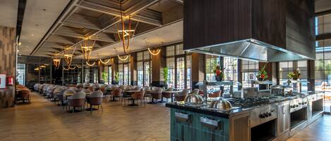 A spacious restaurant with a long counter, multiple seating areas, and a large kitchen.