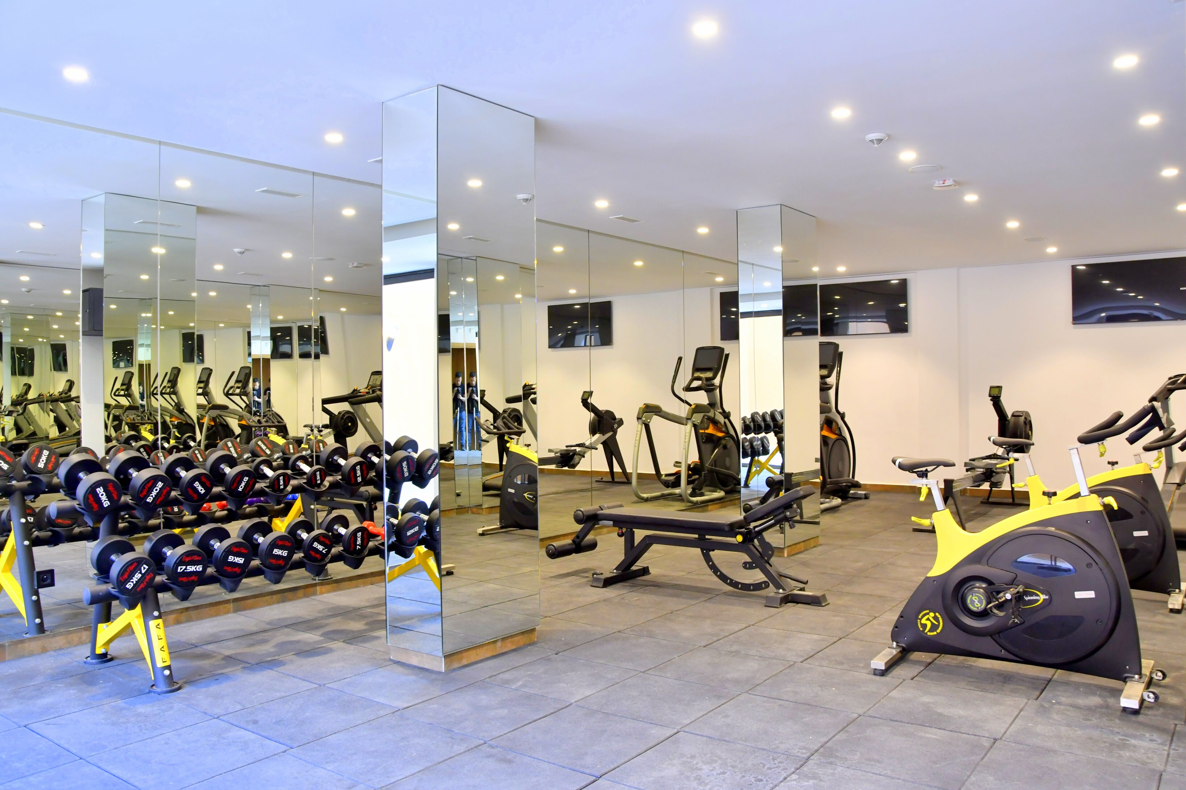 A gym with exercise equipment, mirrors, and a clean, modern design.
