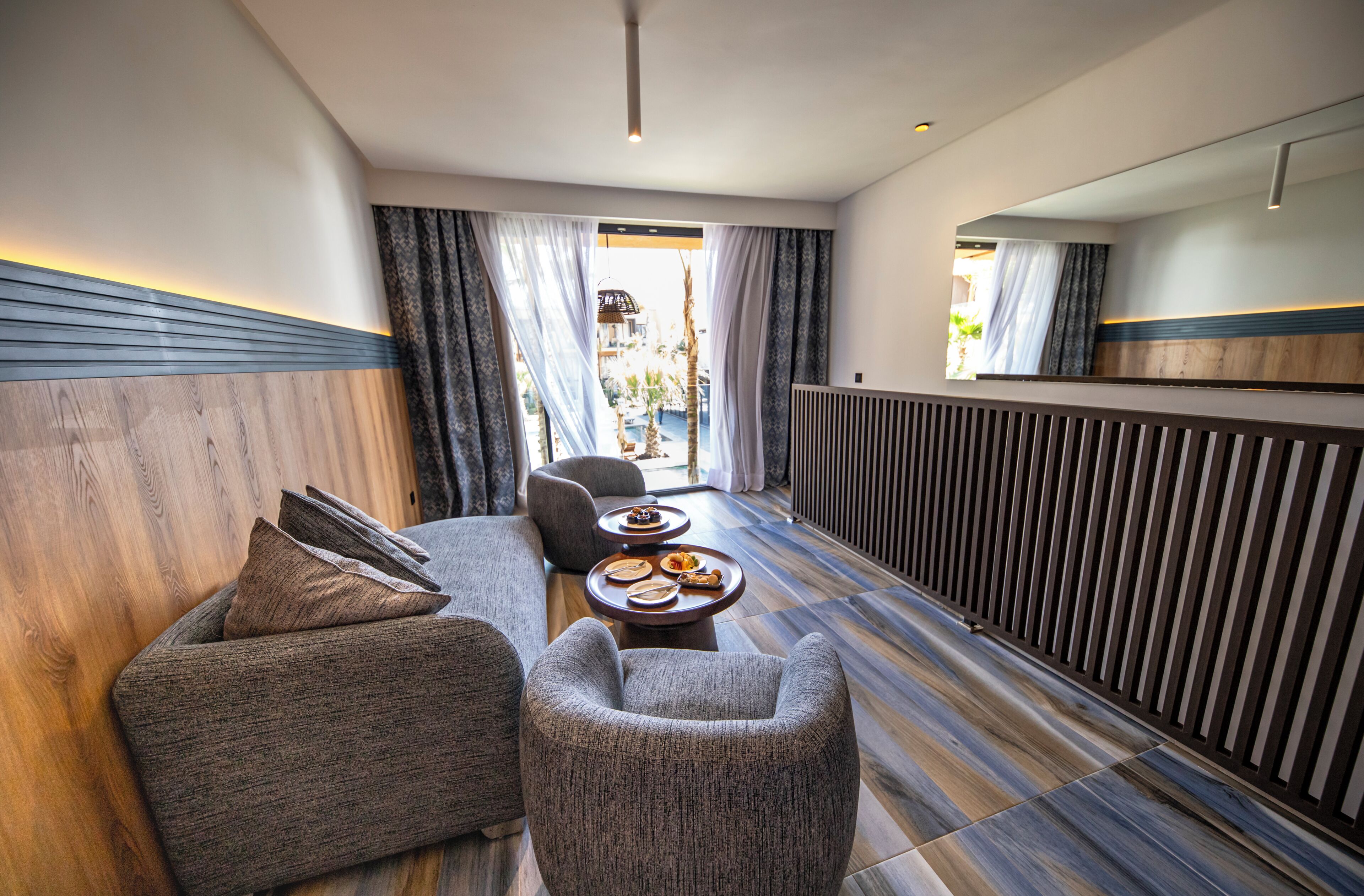 A modern hotel room with a sofa, armchair, and small table.