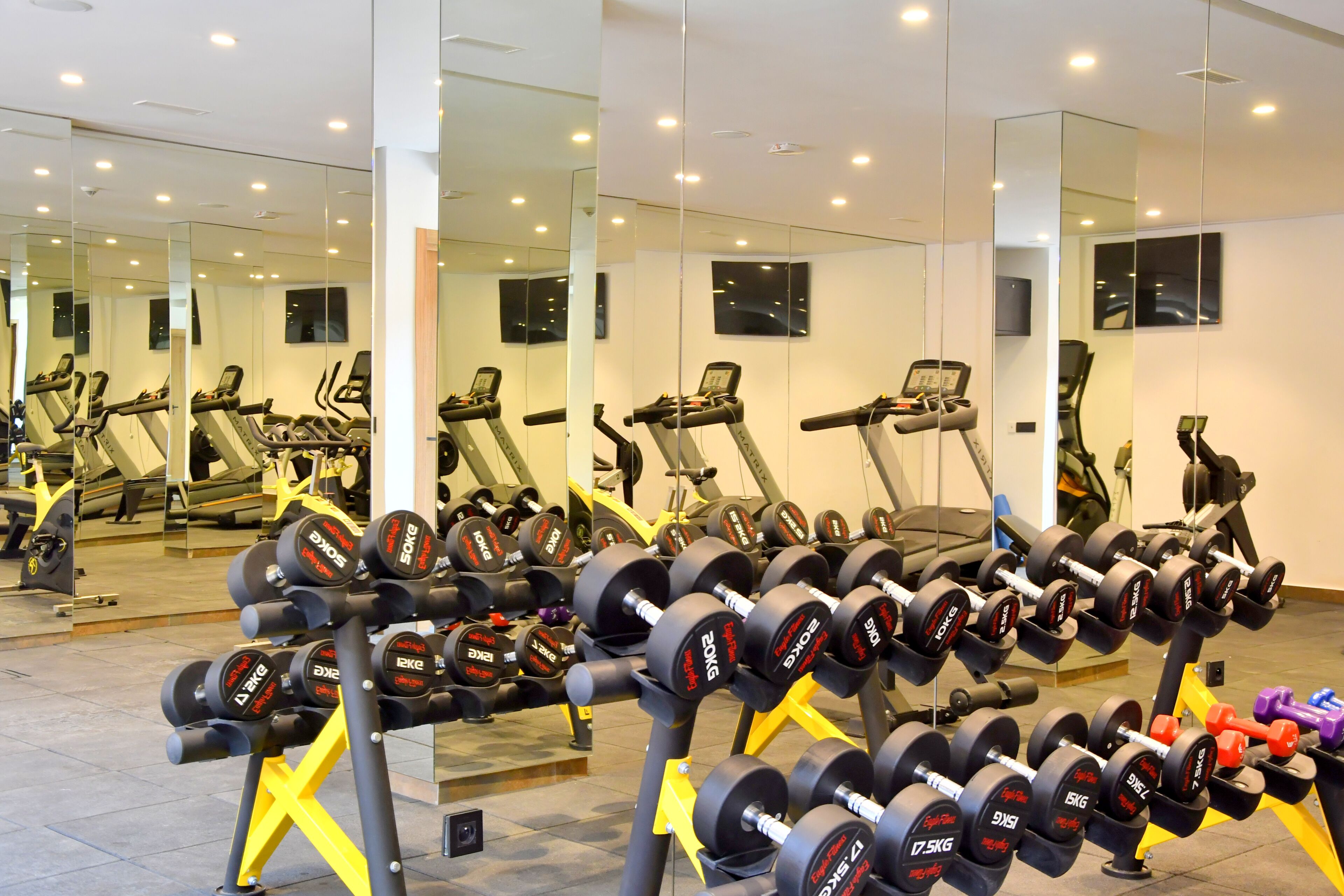 A gym with exercise equipment, mirrors, and treadmills.