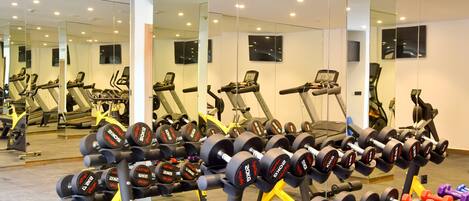 A gym with exercise equipment, mirrors, and treadmills.