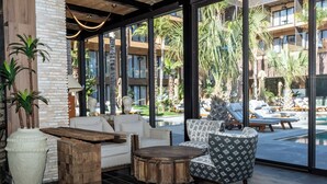 A modern lounge area with a white sofa, patterned armchair, and a wooden coffee table. - Palm Taghazout Hotel (Tamraght)