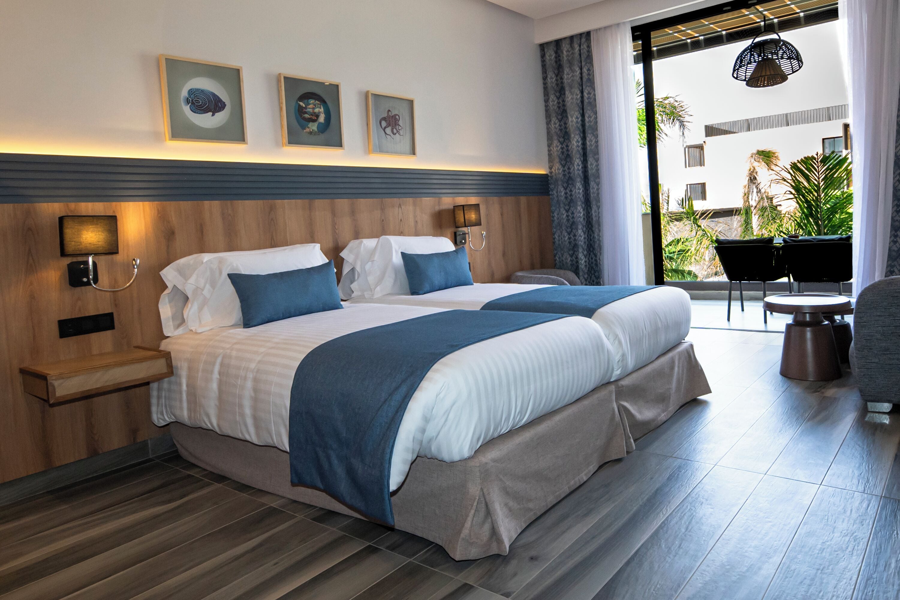 Une chambre d’hôtel comprenant un lit, des tables de chevet, une chaise, une petite table et une vue sur l’extérieur.