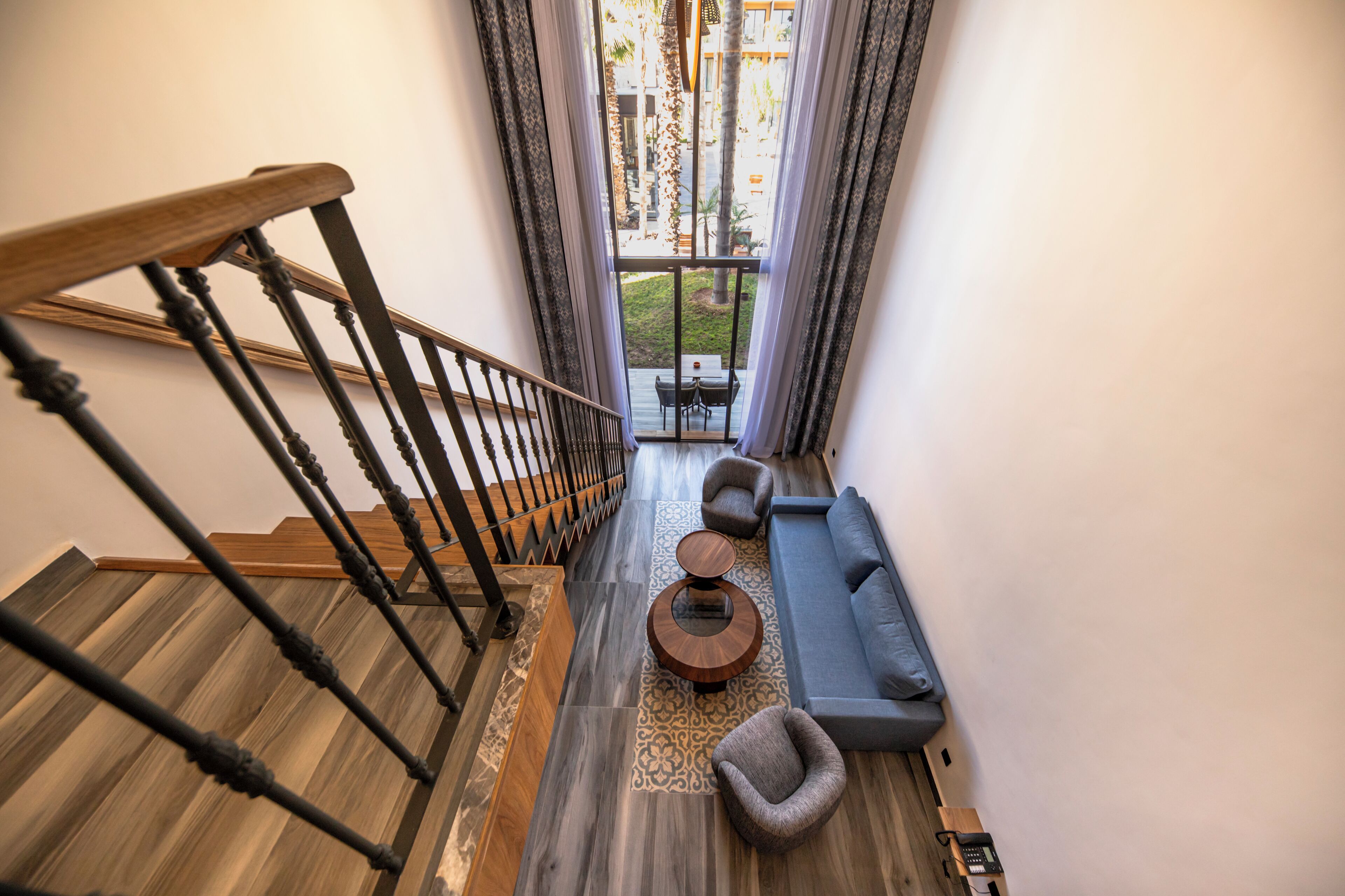 Eine Treppe führt zu einem Wohnbereich mit einer Couch, Sesseln und einem Couchtisch.