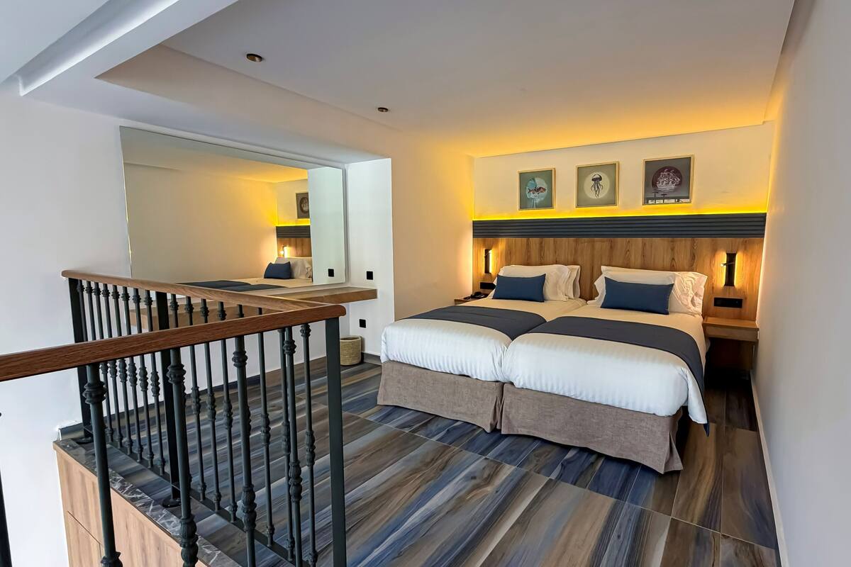 A hotel room with a double bed, a wooden headboard, a nightstand, and a mirror.