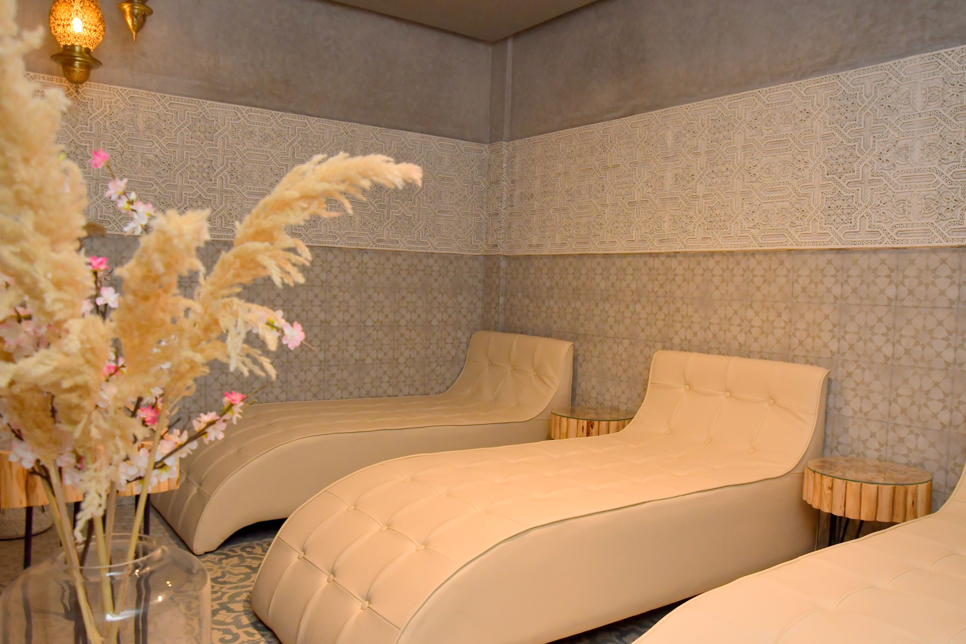 A room with two curved beds, a vase with flowers, and patterned walls.