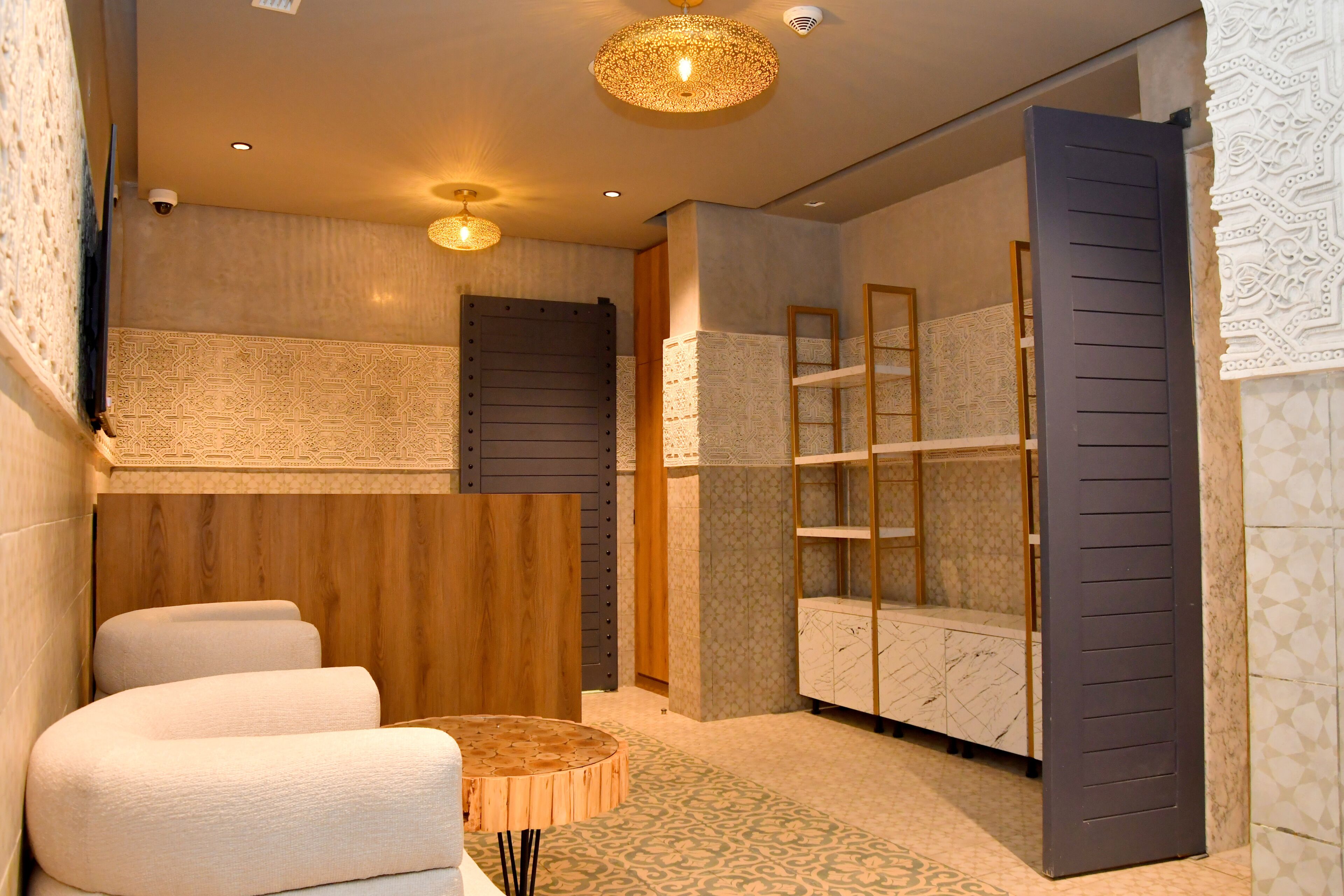 A modern bathroom with a wooden vanity, a round mirror, and a built-in shelf unit.