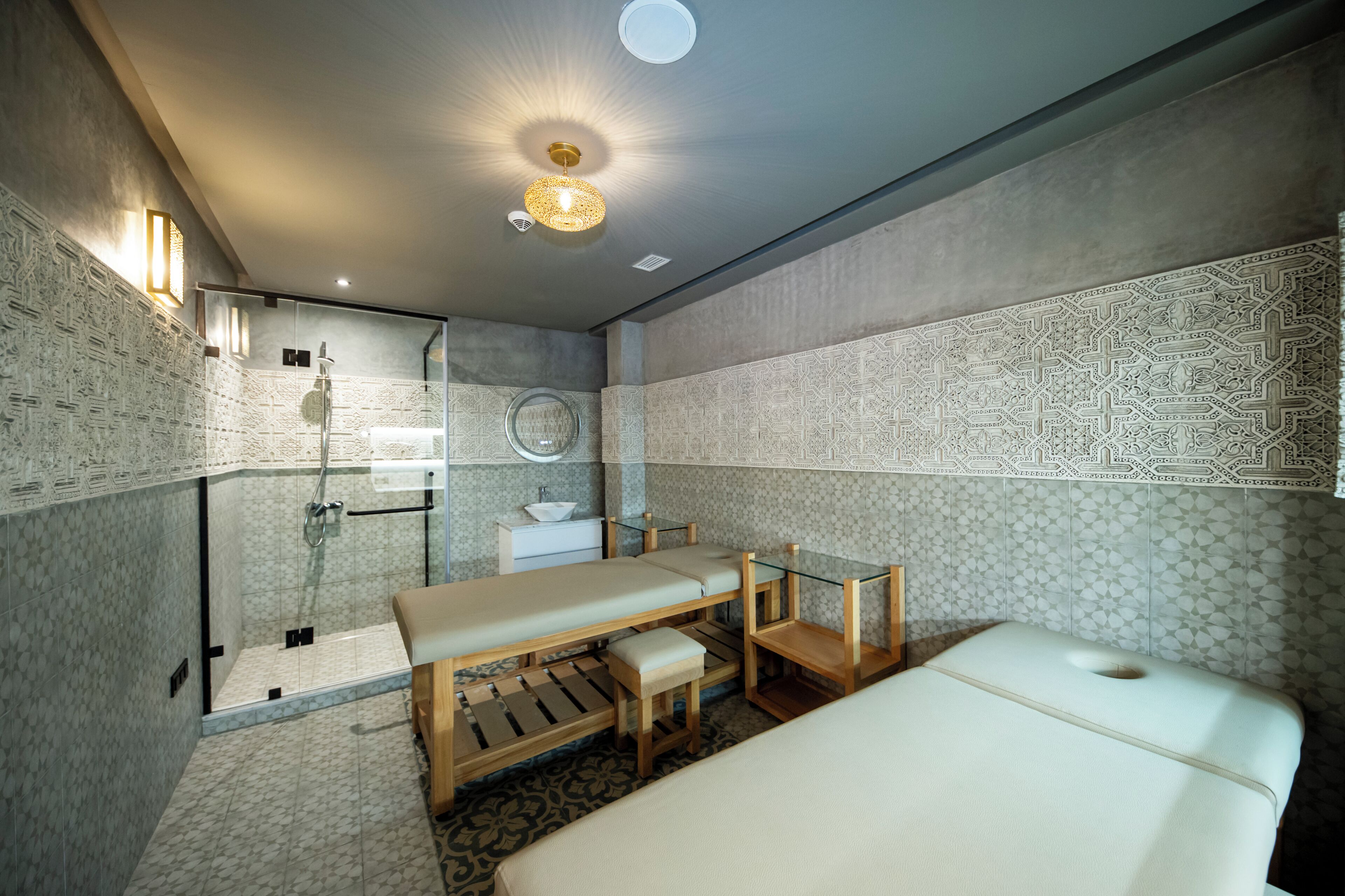 A modern bathroom with a shower, a bench, a massage table, and patterned walls.