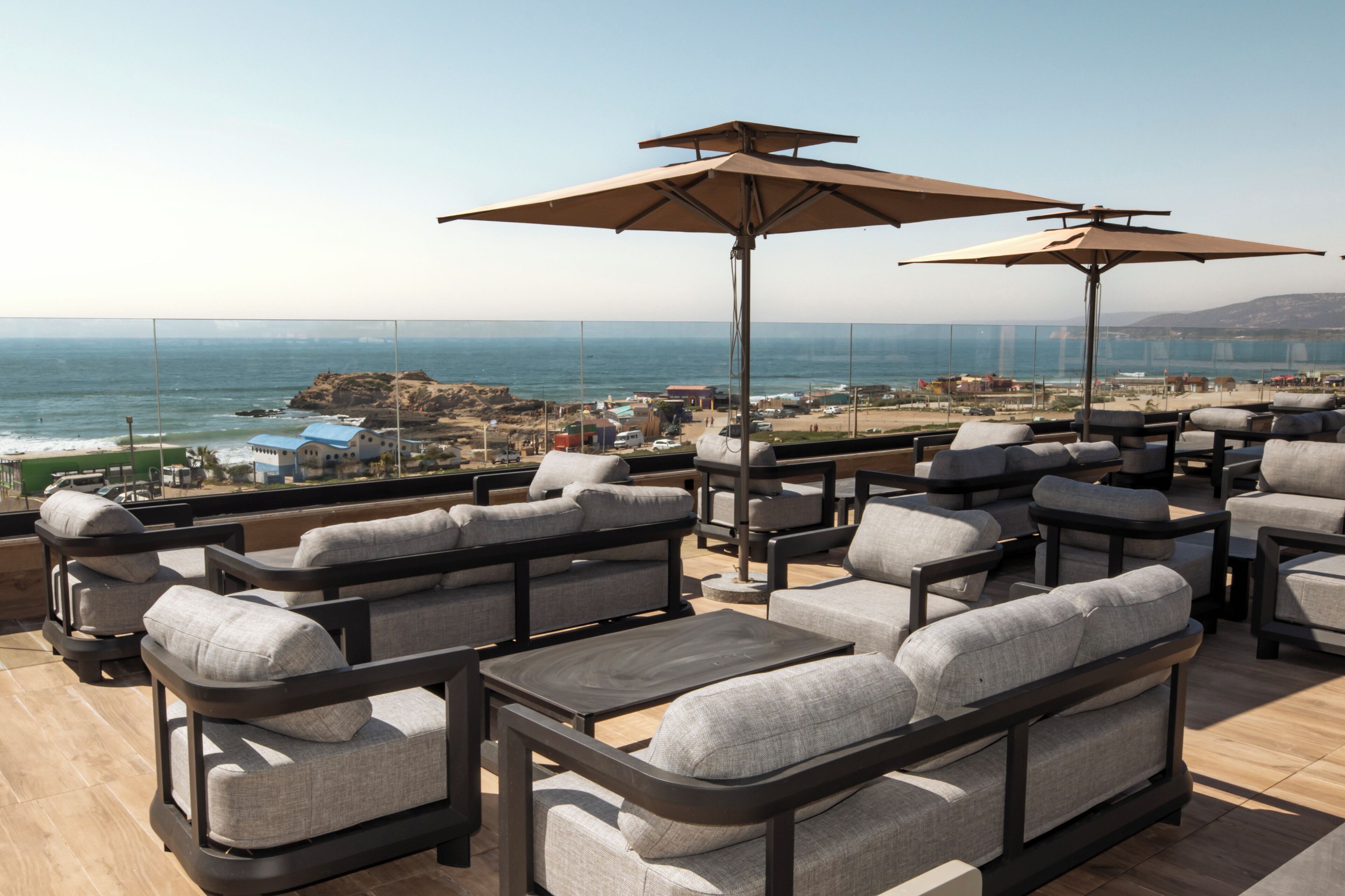 A rooftop terrace with outdoor seating, a view of the ocean, and a clear sky.