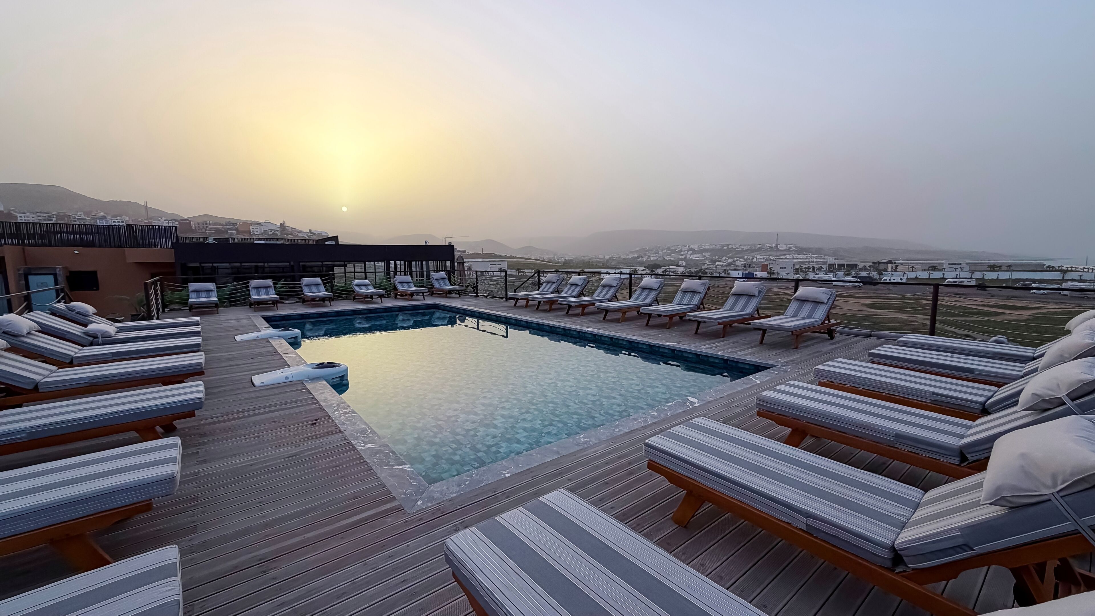 A rooftop pool with lounge chairs and a view of the cityscape.